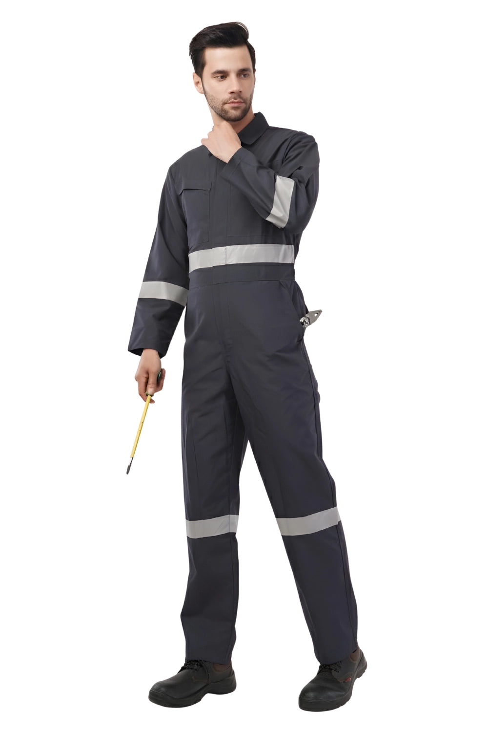 Man wearing dark gray industrial coverall with reflective bands on sleeves, waist, and legs, holding a yellow screwdriver
