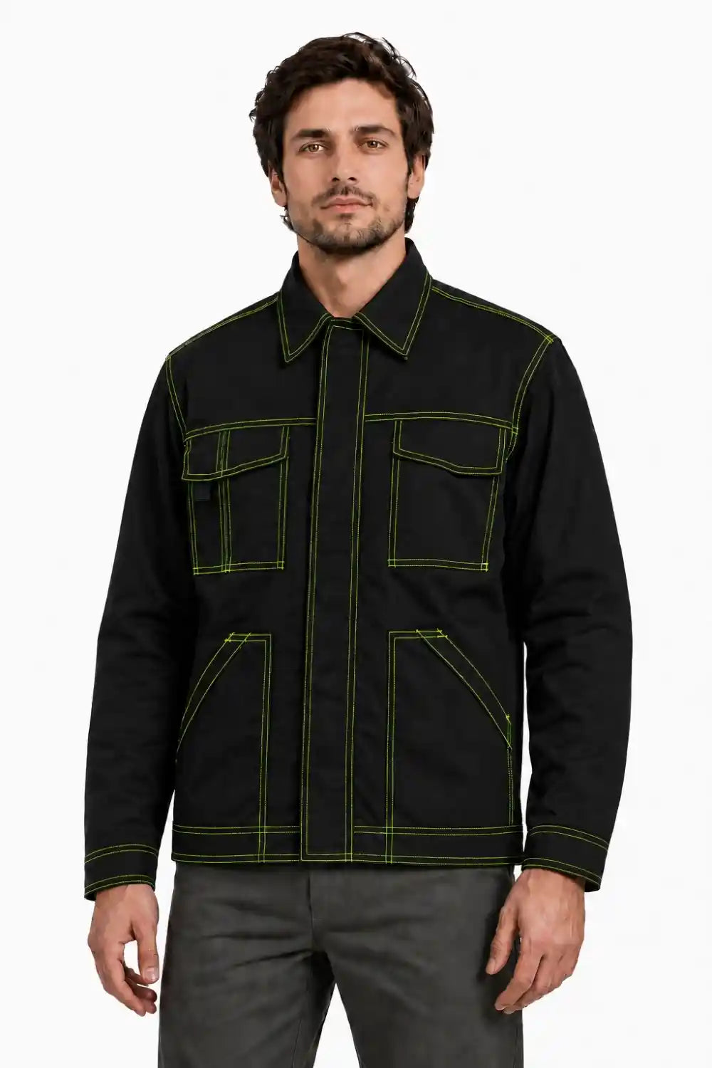 A man wearing a black utility-style jacket with high contrast lime green contrast stitching, paired with gray trousers, against a plain white background.