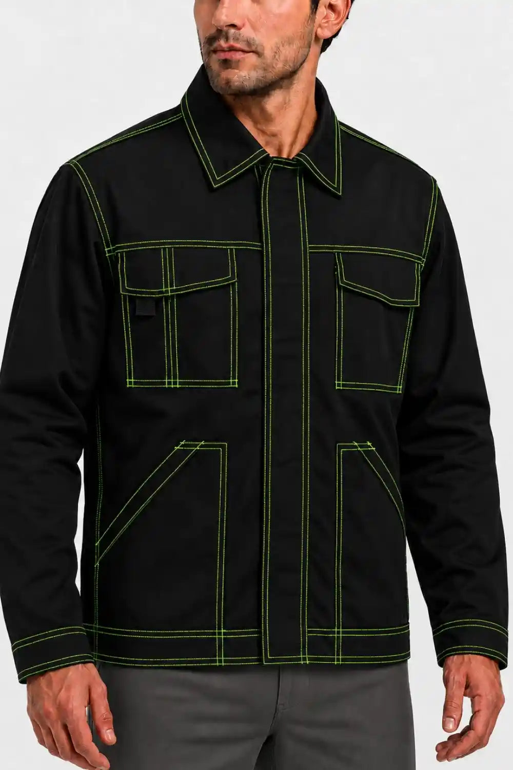 A man wearing a black utility-style jacket with bright green contrast stitching, shown from the chest down against a light gray studio background.