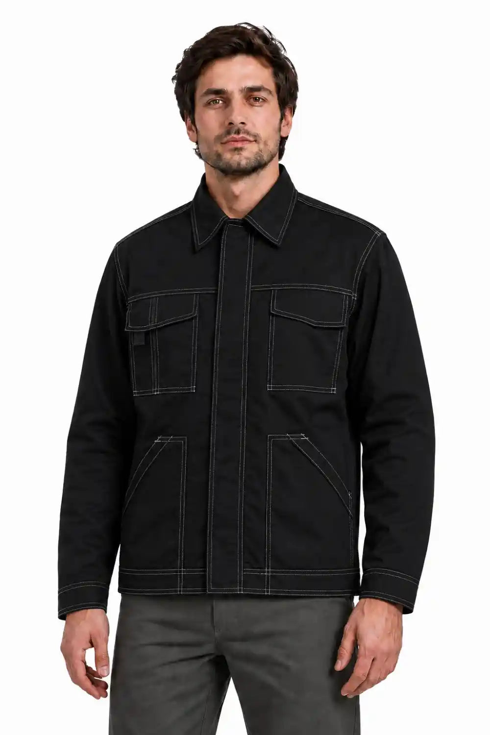 A man wearing a black utility jacket with contrast white stitching and gray pants, photographed against a plain white studio background.