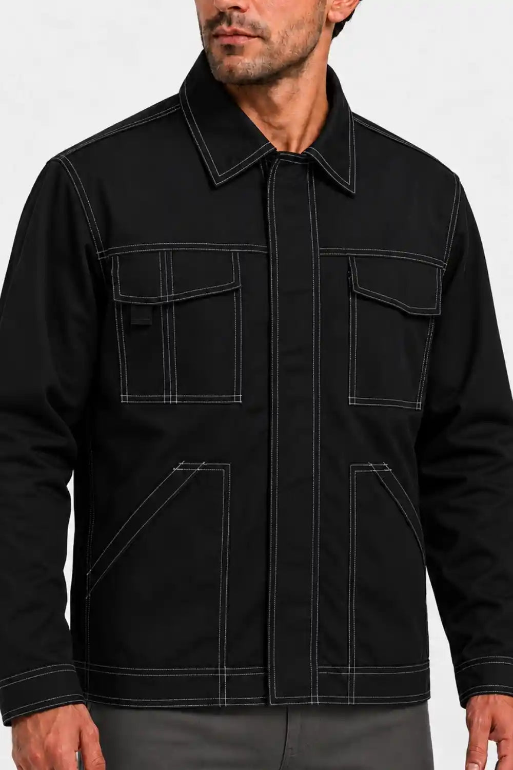 A man wearing a black utility jacket with high contrast white contrast stitching, shown from the chin down against a light gray background.