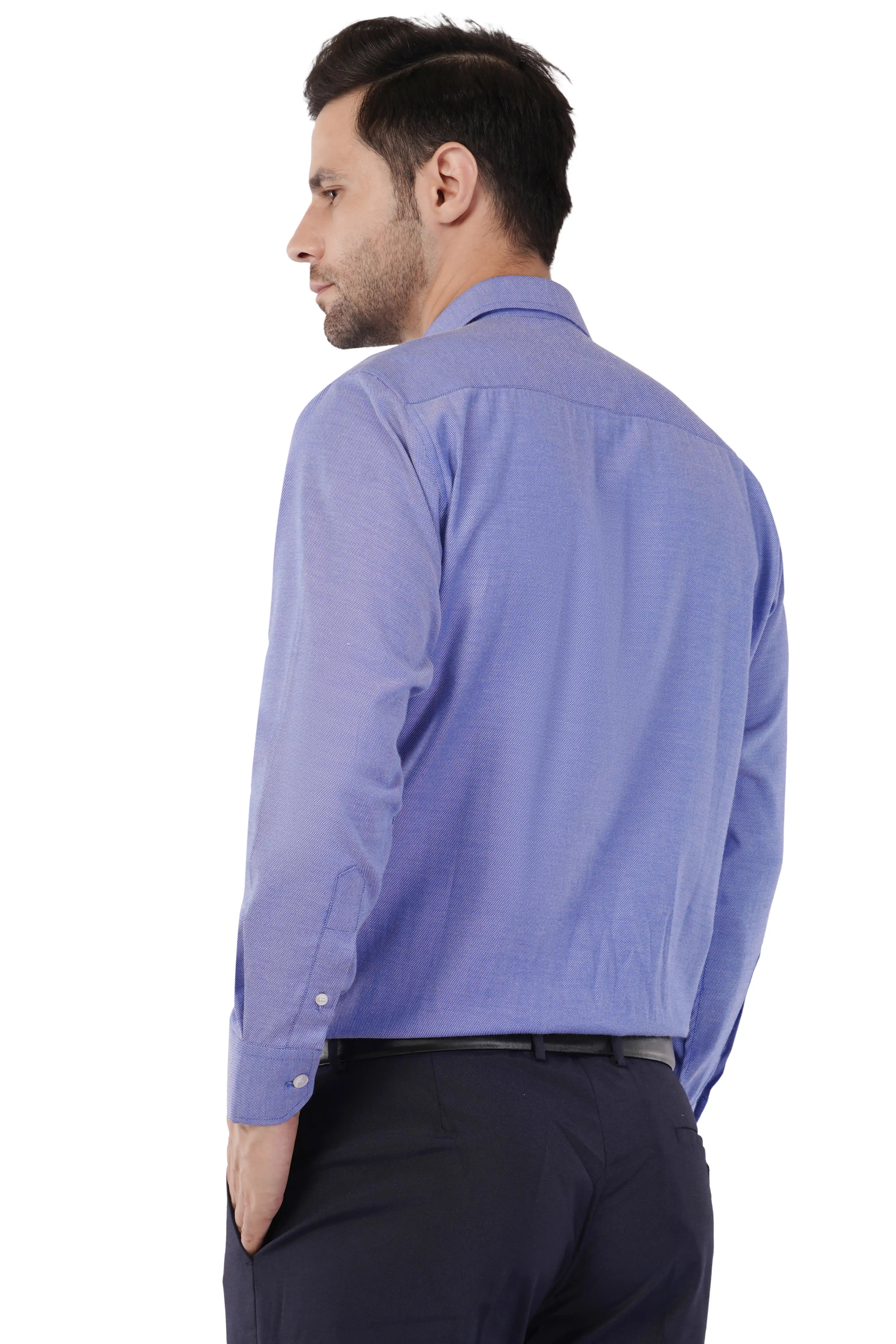 Man wearing a blue dress shirt from Atacama and dark pants on a white background