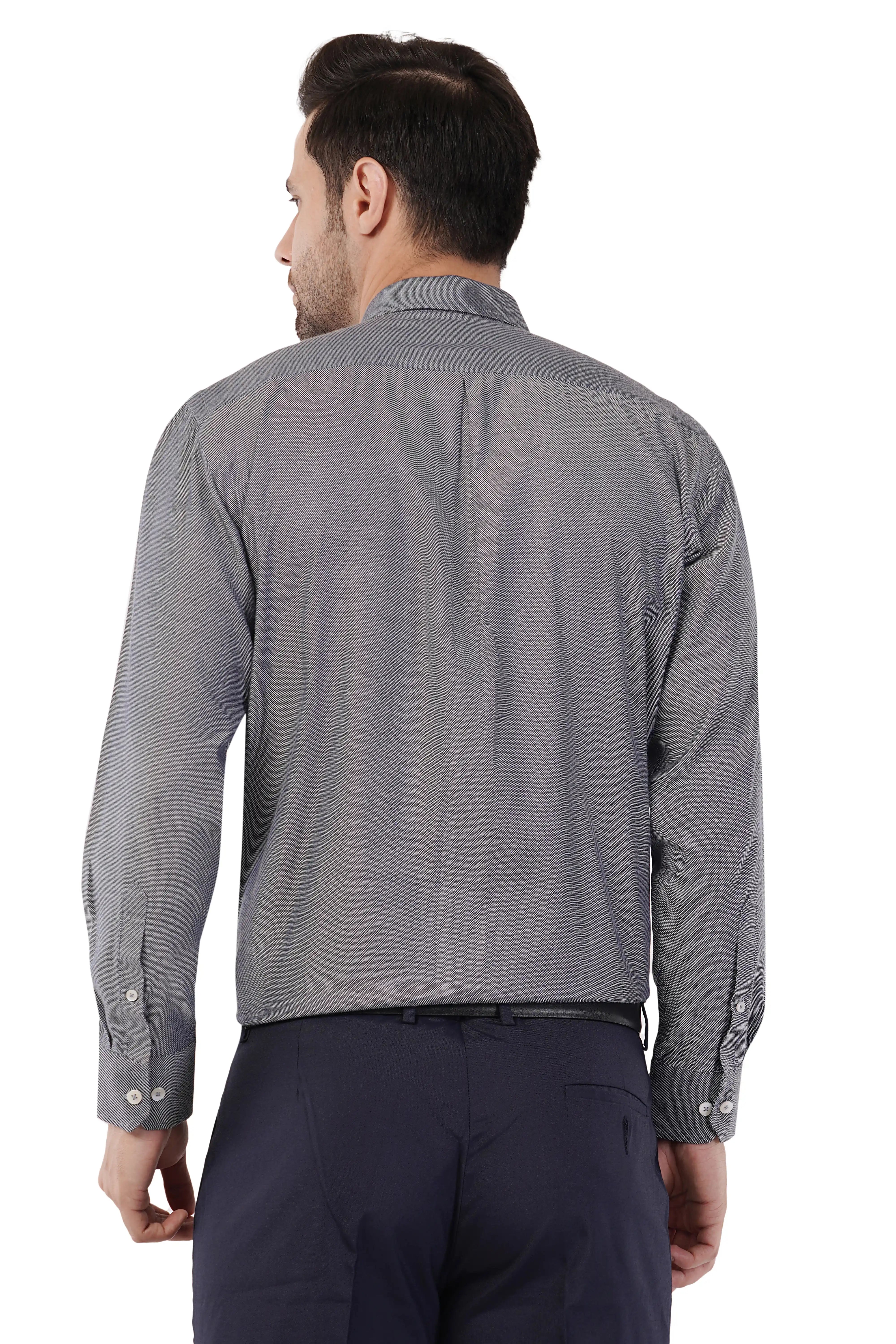 Man wearing a gray patterned Atacama shirt and dark pants on a white background