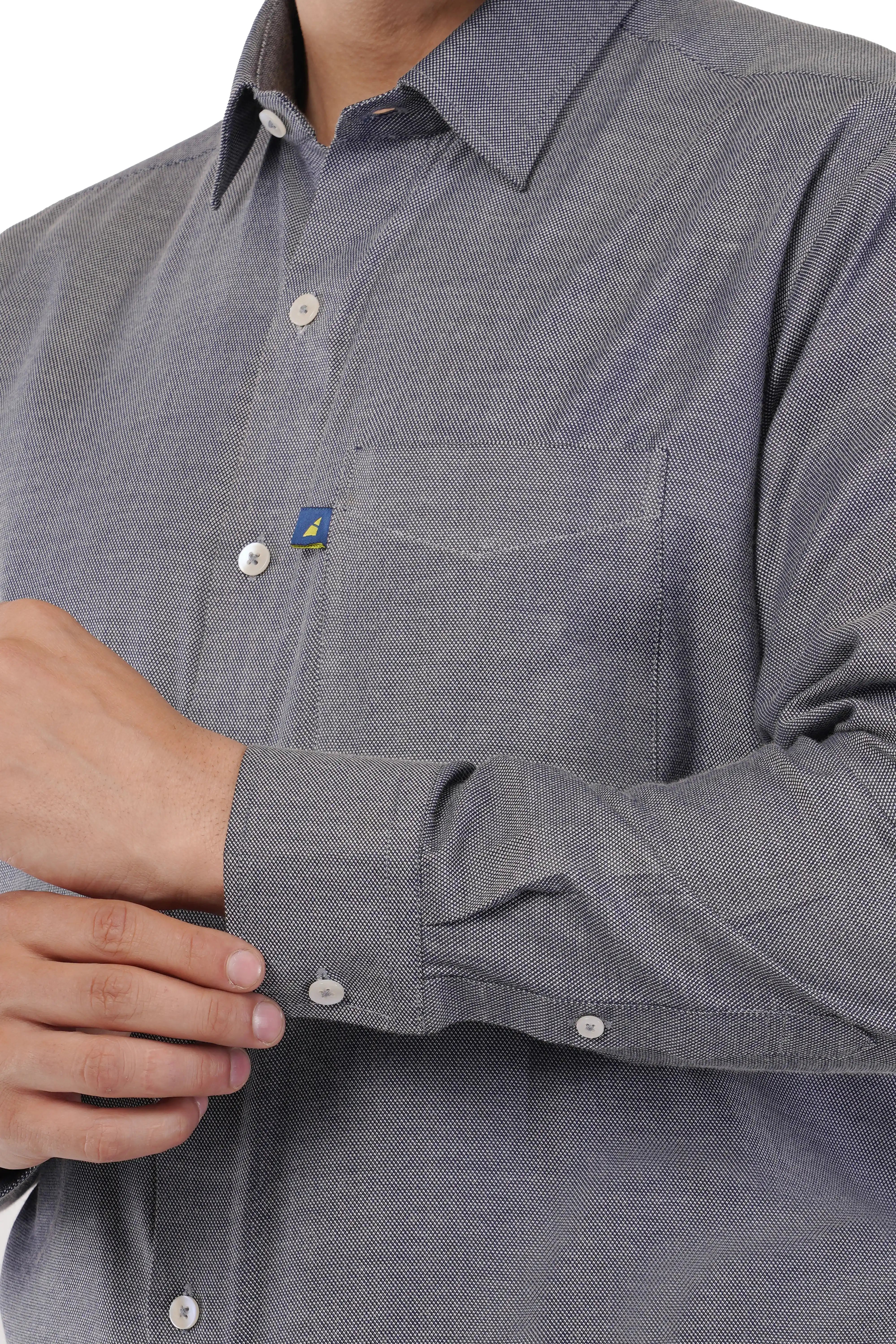 Close-up of a person wearing a gray button-up Atacama shirt with a brand logo on the chest.