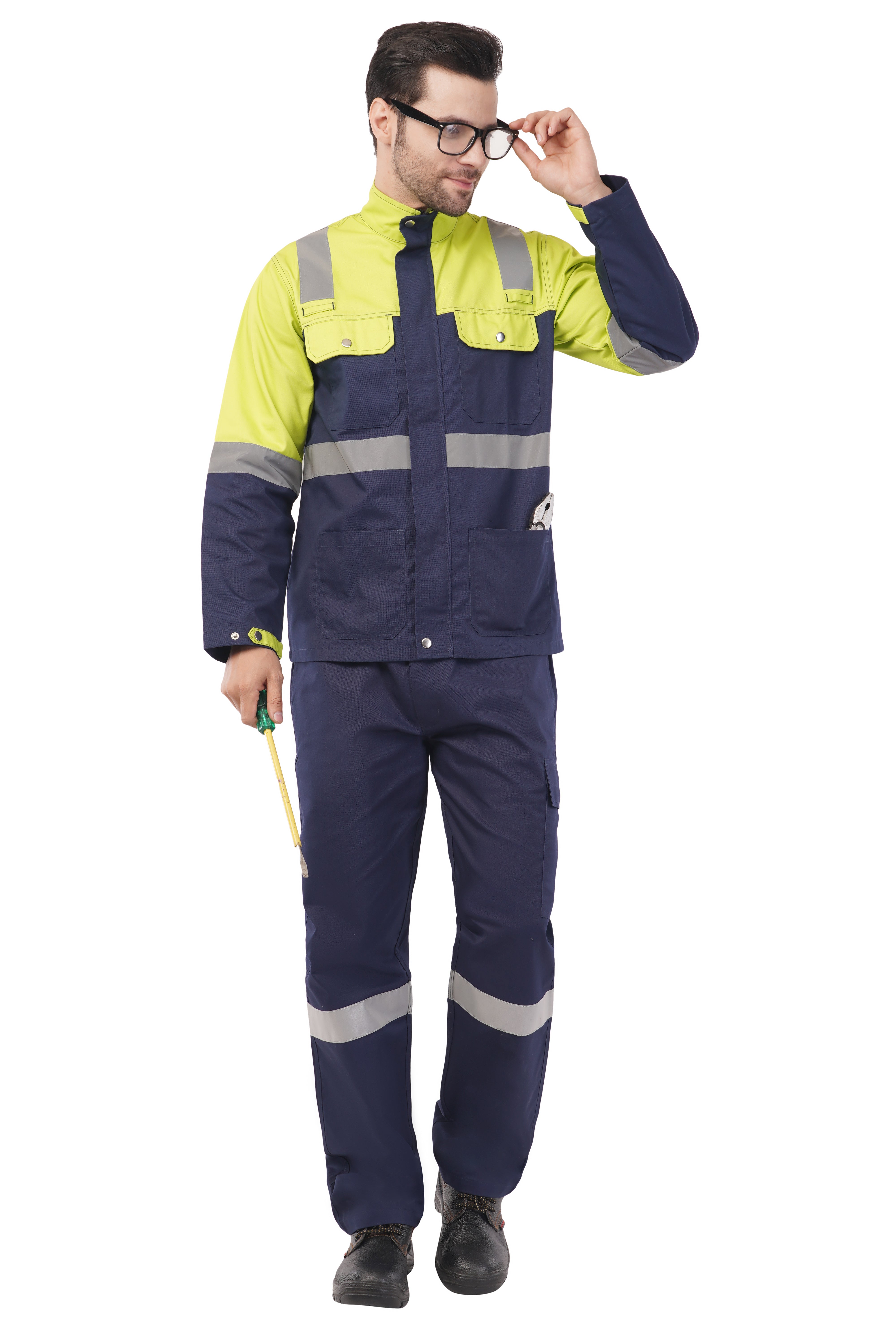 Man wearing navy blue and yellow safety jacket and trousers with reflective strips, holding a screwdriver and pliers in