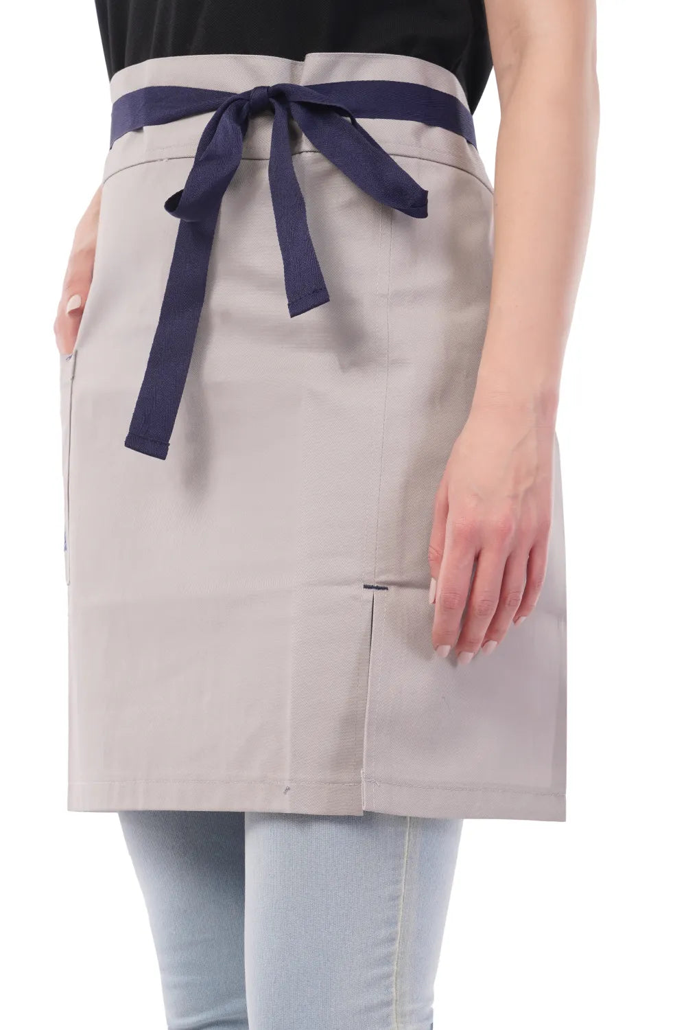 Person wearing a beige Atacama apron with a navy blue tie on a white background