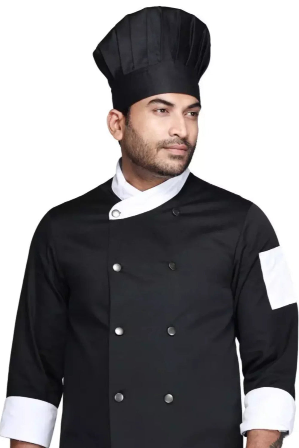 Person wearing a black Atacama chef's coat with white cuffs and a black hat on a white background.